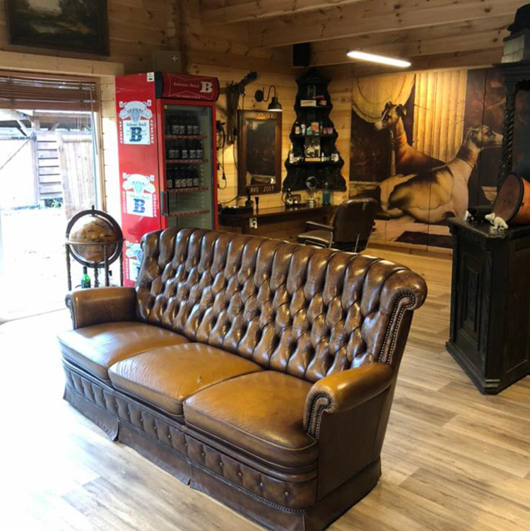 Chesterfield-Sofa im Wartebereich, dahinter der Friseurplatz